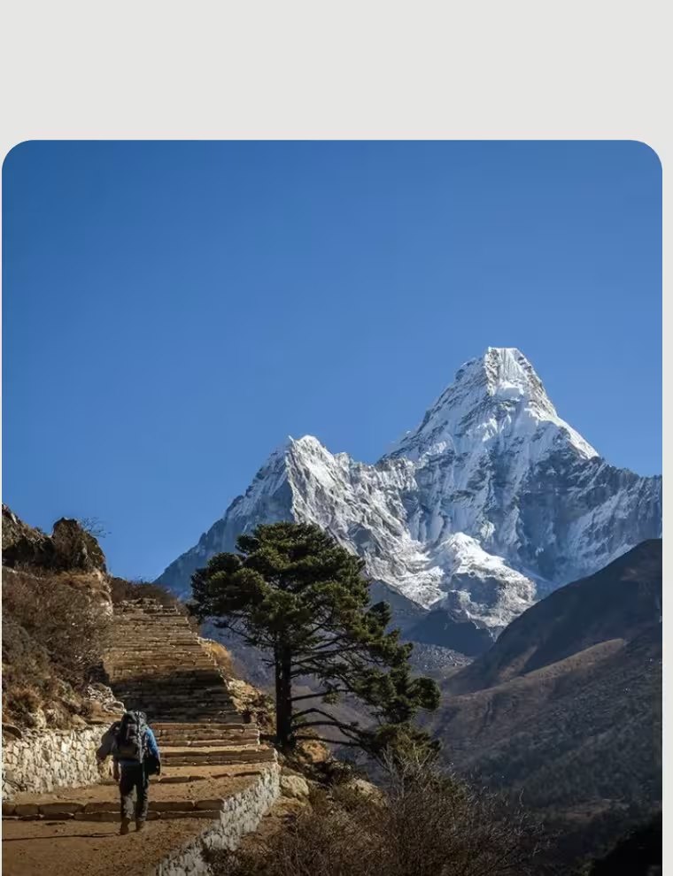 A trekker on a ridge below the snow peaks of the Himalaya
